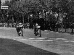 Llegada de infarto en el XV Gran Premio de Montjuic de 1959 en a clase de 125 cc. Por unos pocos centímetros sobre la misma línea de meta, se impuso Juan "Tey" Elizalde con <span style="color: #ff0000;"><em><strong>Montesa</strong></em></span> a Johnny Grace con Bultaco.