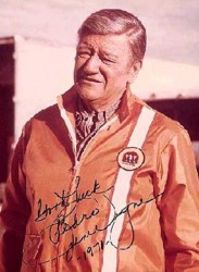 En 1971, después del rodaje de una película, el popular actor John Wayne donde aparece con un mono de mecánico de <span style="color: #ff0000;"><em><strong>Montesa</strong></em></span>, dedicó esta fotografía a su amigo Pere Permanyer (patrón de <span style="color: #ff0000;"><em><strong>Montesa</strong></em></span>).